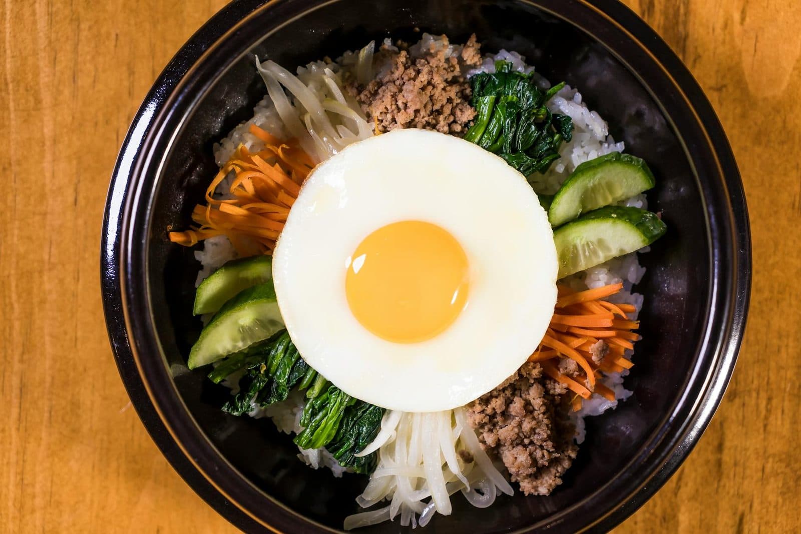 Korean bibimbap bowl with rice, egg, beef, vegetables, and gochujang