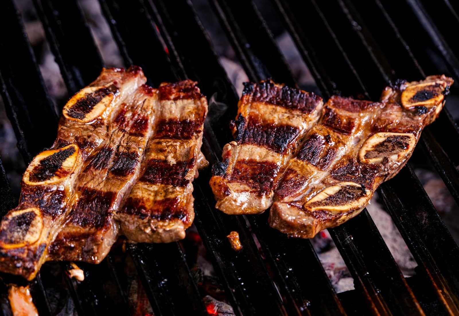 Korean galbi-style beef short ribs grilling over charcoal with deep sear marks