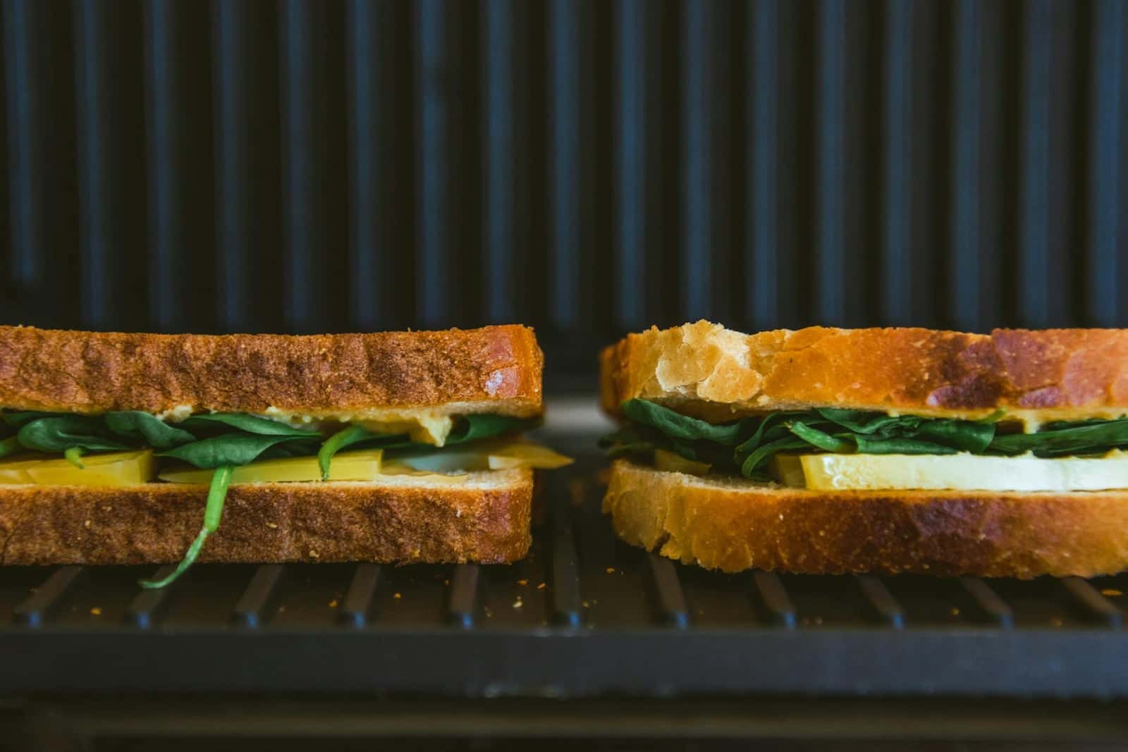 Kimchi grilled cheese sandwiches toasting on a grill with browned bread and green filling