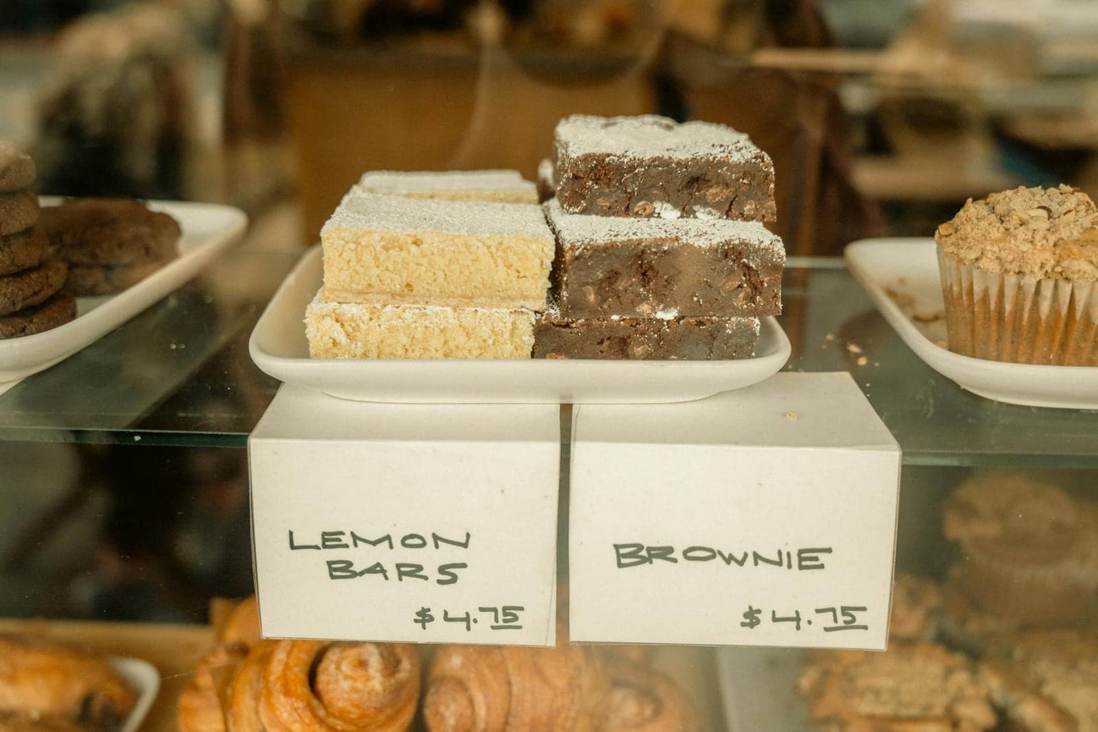 Lemon bars displayed in a bakery case with powdered tops and clean square cuts