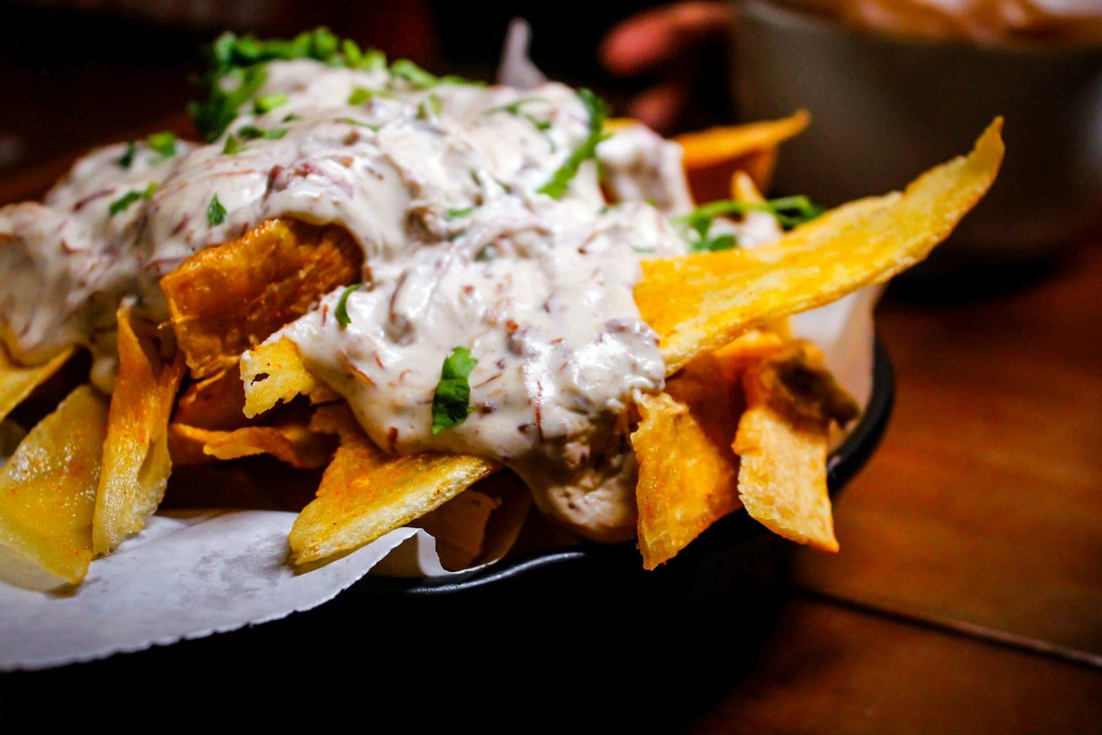 Loaded sheet pan nachos topped with cheese sauce, cilantro, and toppings in a metal pan