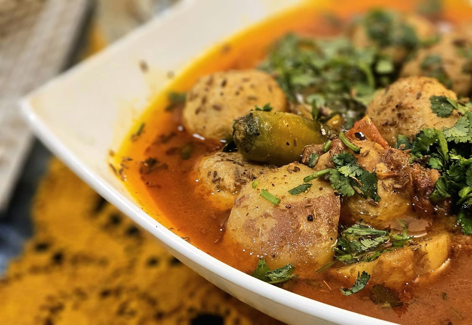 Massaman curry-style potato curry with herbs in a white bowl