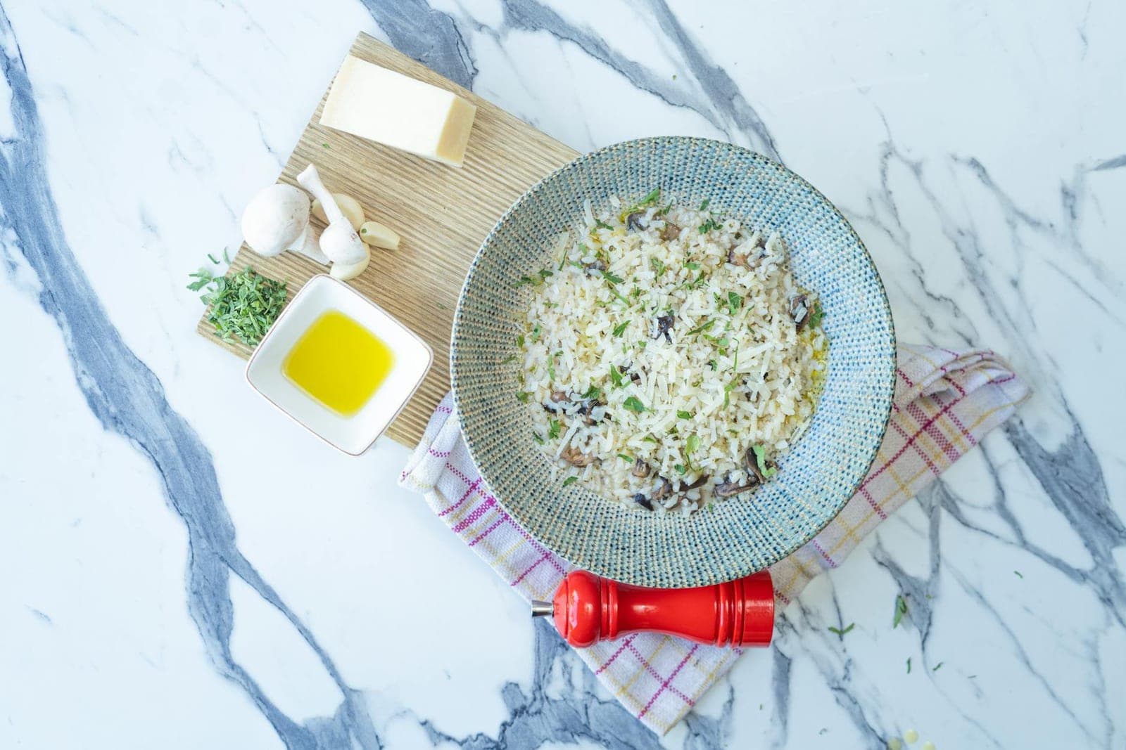 Mushroom and pea risotto with herbs and grated cheese in a pale blue bowl