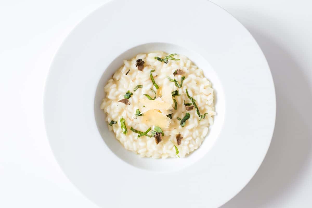 Creamy mushroom risotto on a white plate with herbs and Parmesan
