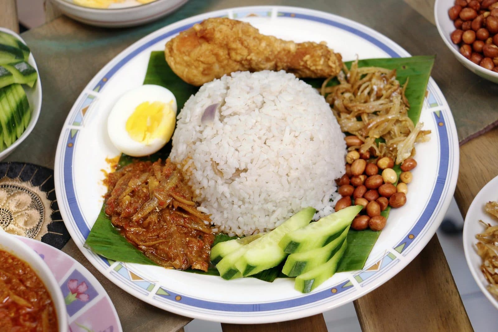 Nasi lemak coconut rice with fried chicken, sambal, peanuts, cucumber, and boiled egg on a plate