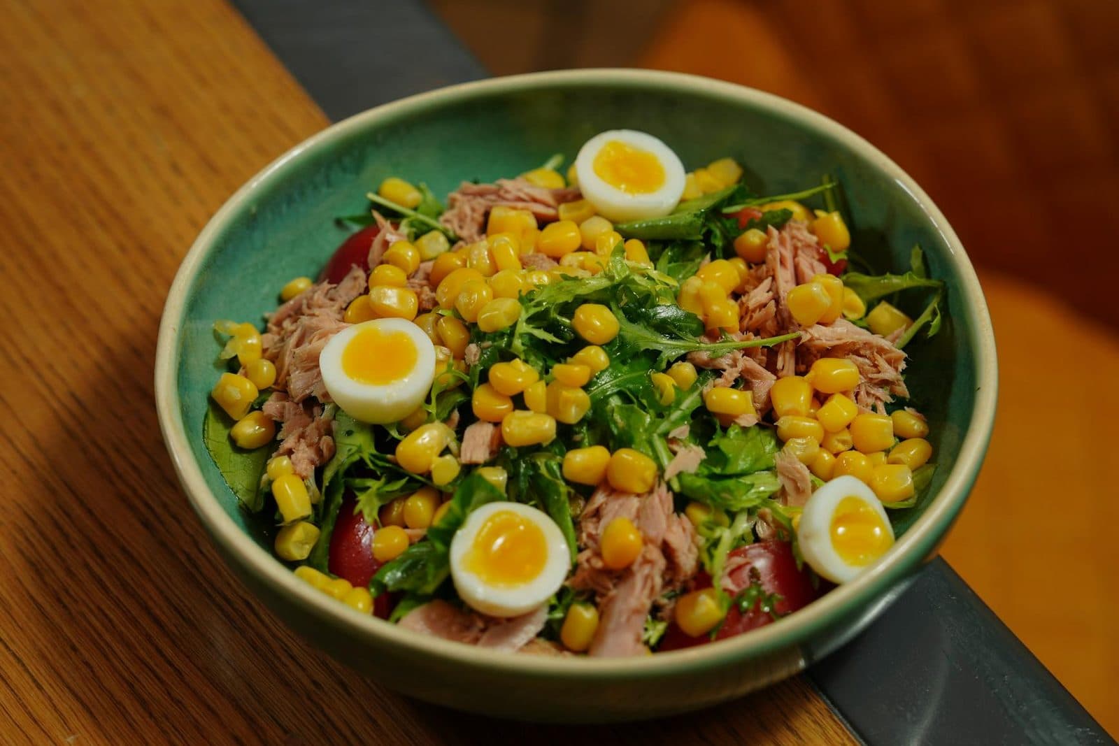 Nicoise salad bowl with tuna, eggs, vegetables, corn, and greens
