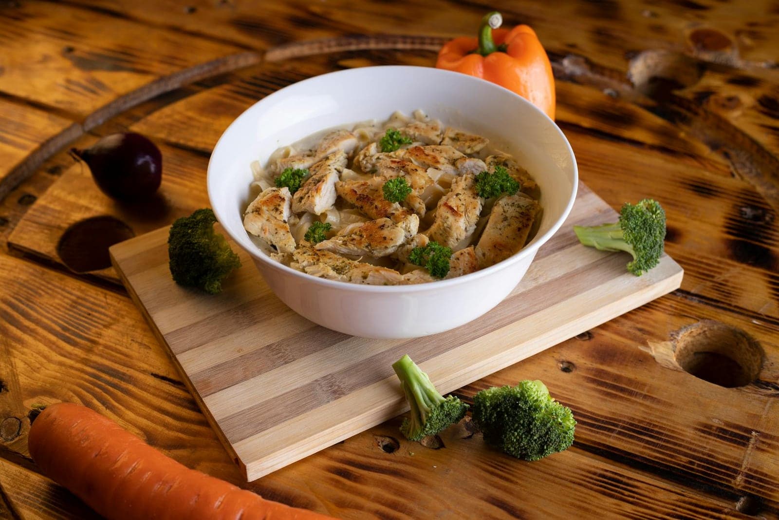 One-pot chicken orzo in a white bowl with shredded chicken, herbs, and vegetables on a wooden table