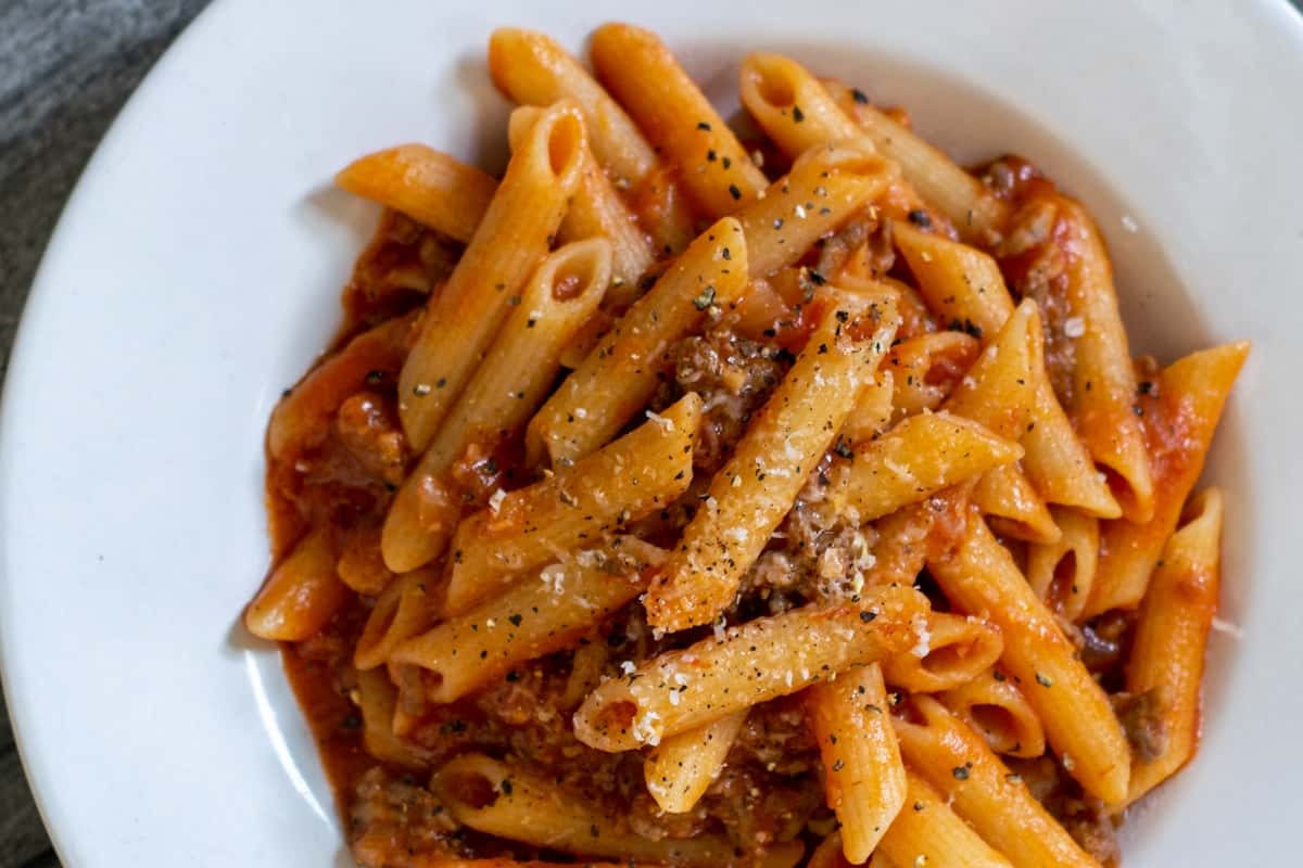 Creamy Tuscan penne pasta with tomato sauce and grated Parmesan