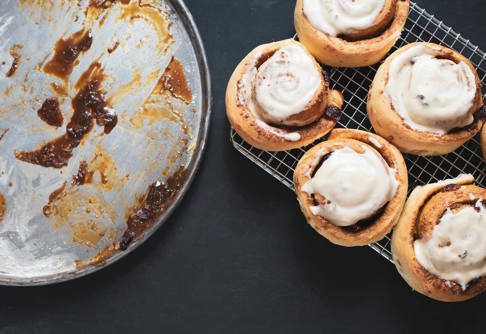 Overnight cinnamon rolls with icing cooling beside a baking tray