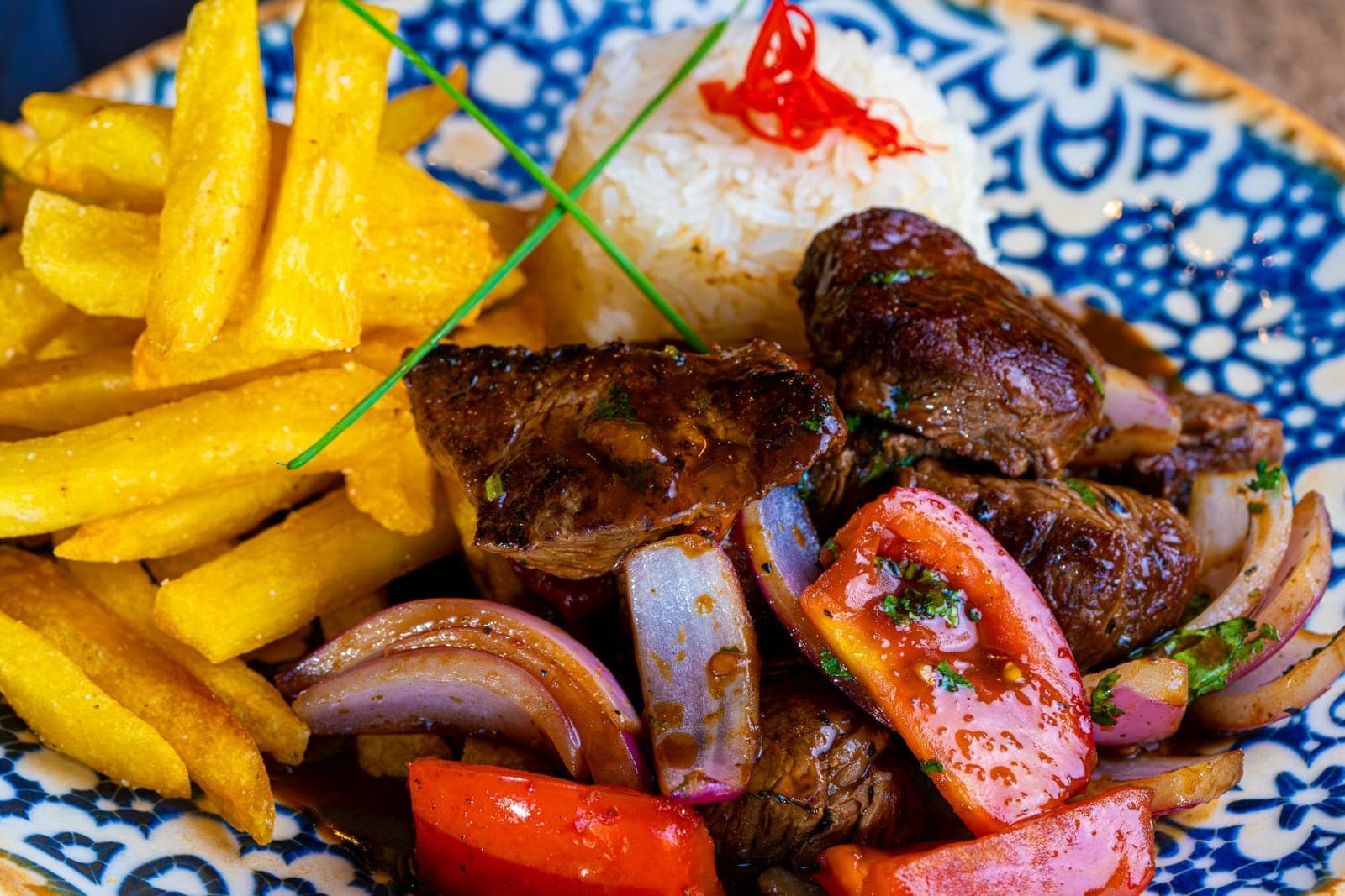 Peruvian lomo saltado with strips of beef, tomatoes, onions, fries, and rice
