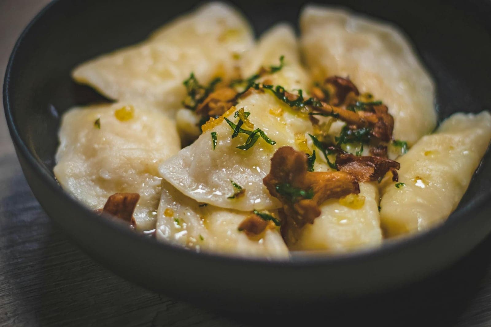 Pierogi with mushrooms and herbs in a black bowl