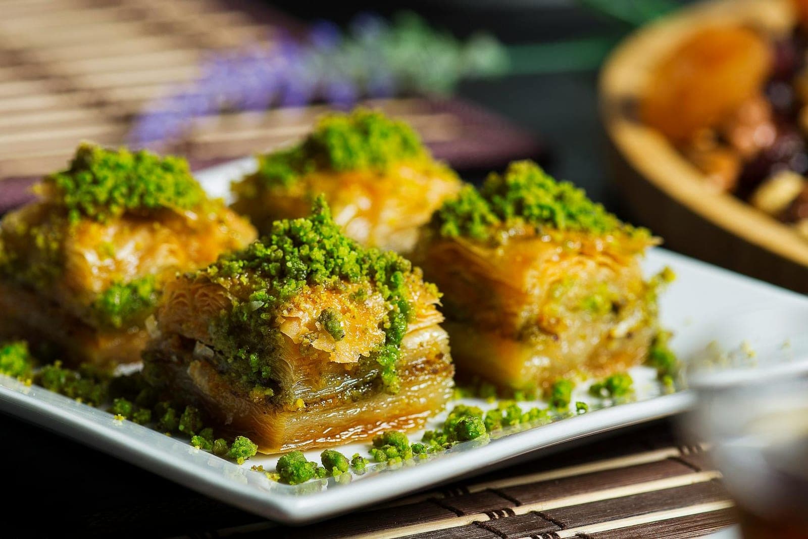 Pistachio baklava pieces with green pistachio topping on a serving plate