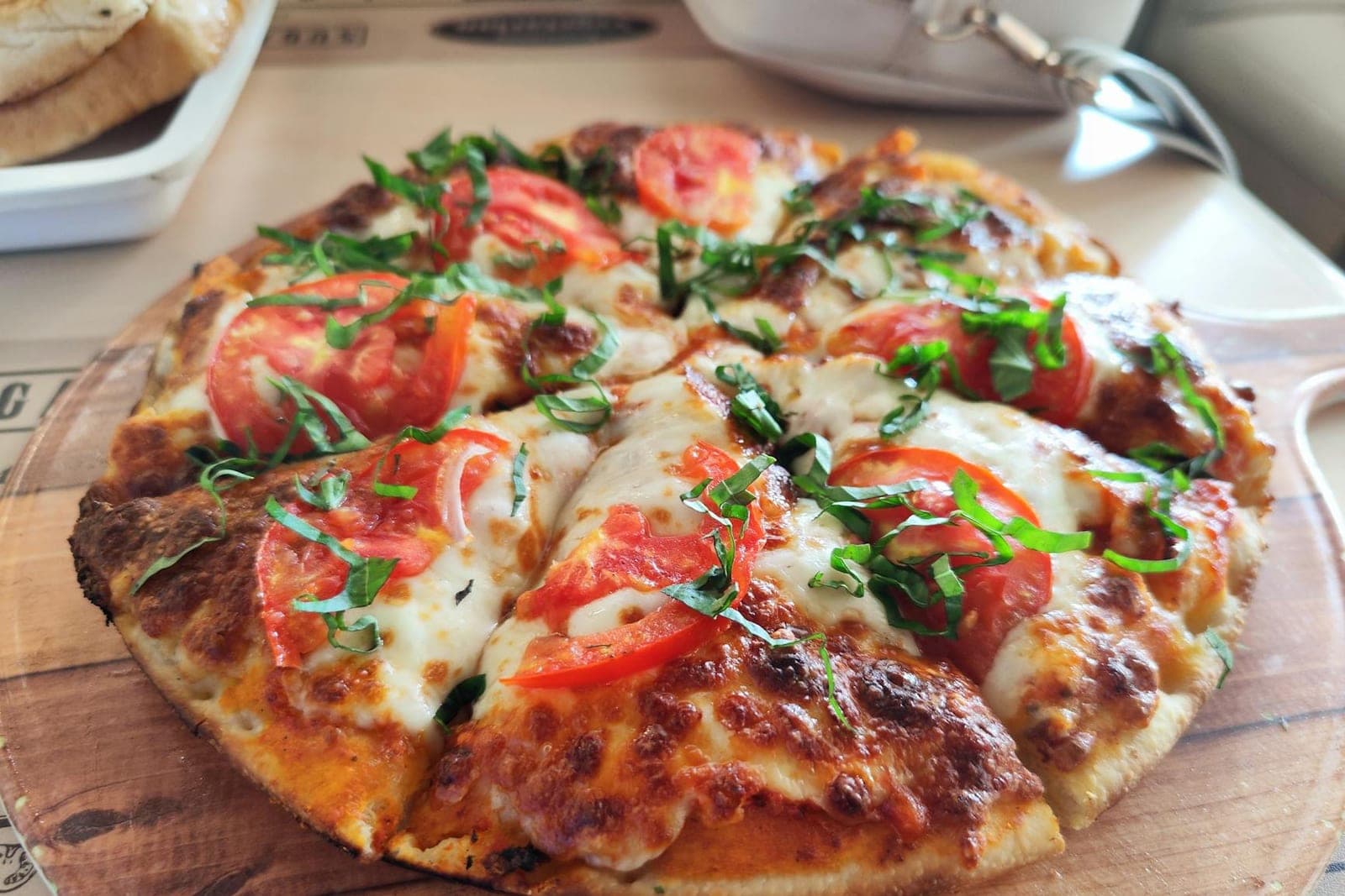 Pizza Margherita Napoletana with tomato, mozzarella, basil, and a blistered crust on a wooden board