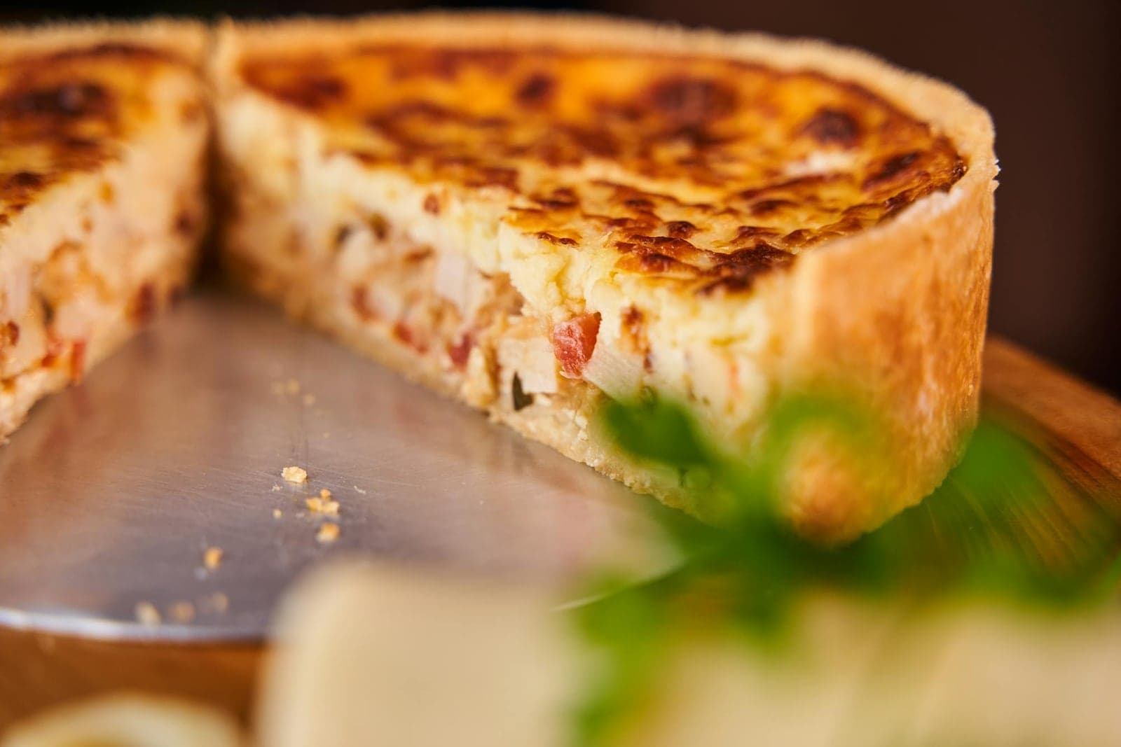 Quiche Lorraine slice with golden custard and browned crust on a serving board