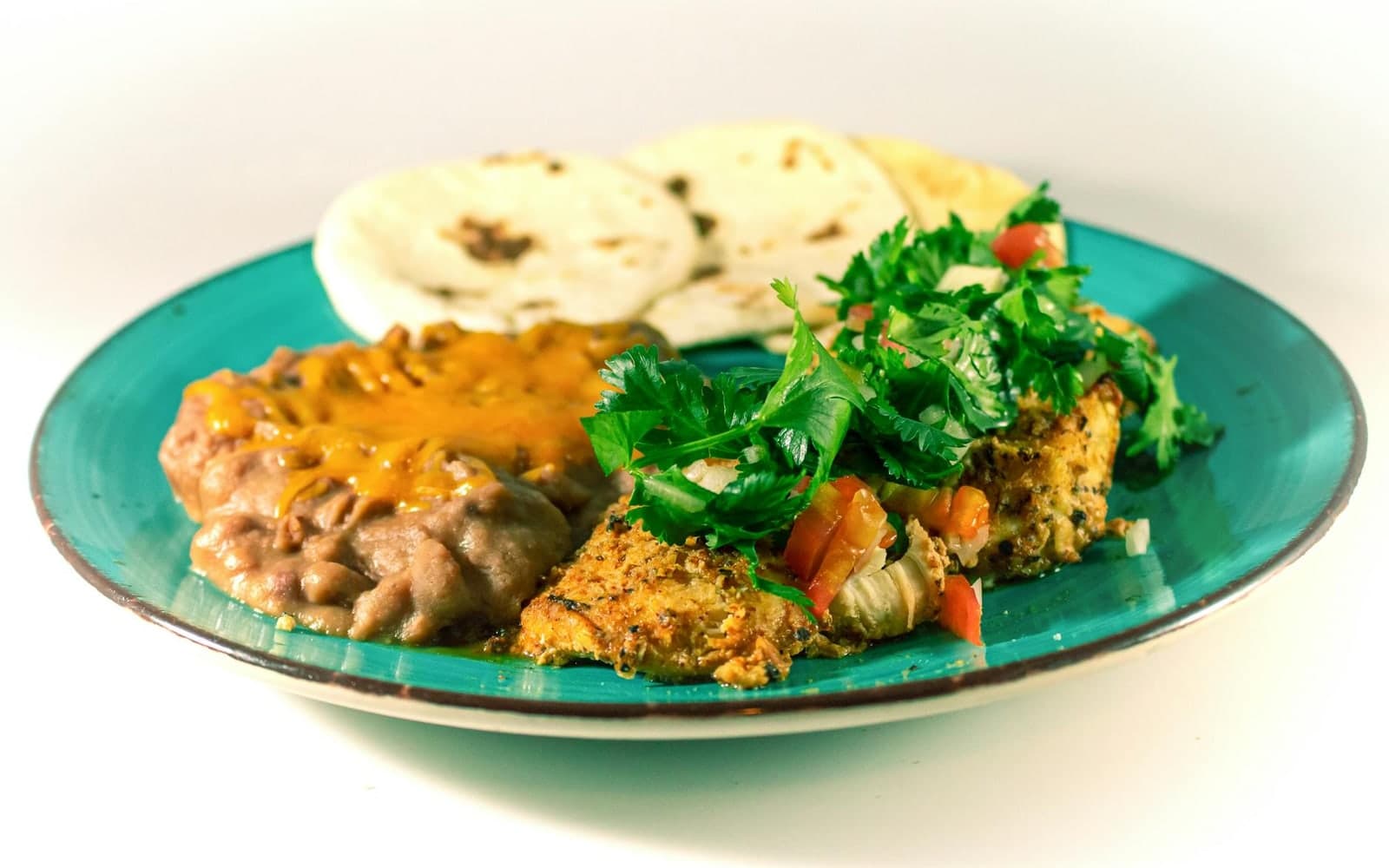 Refried beans served with rice, plantains, greens, and a warm Mexican-style plate