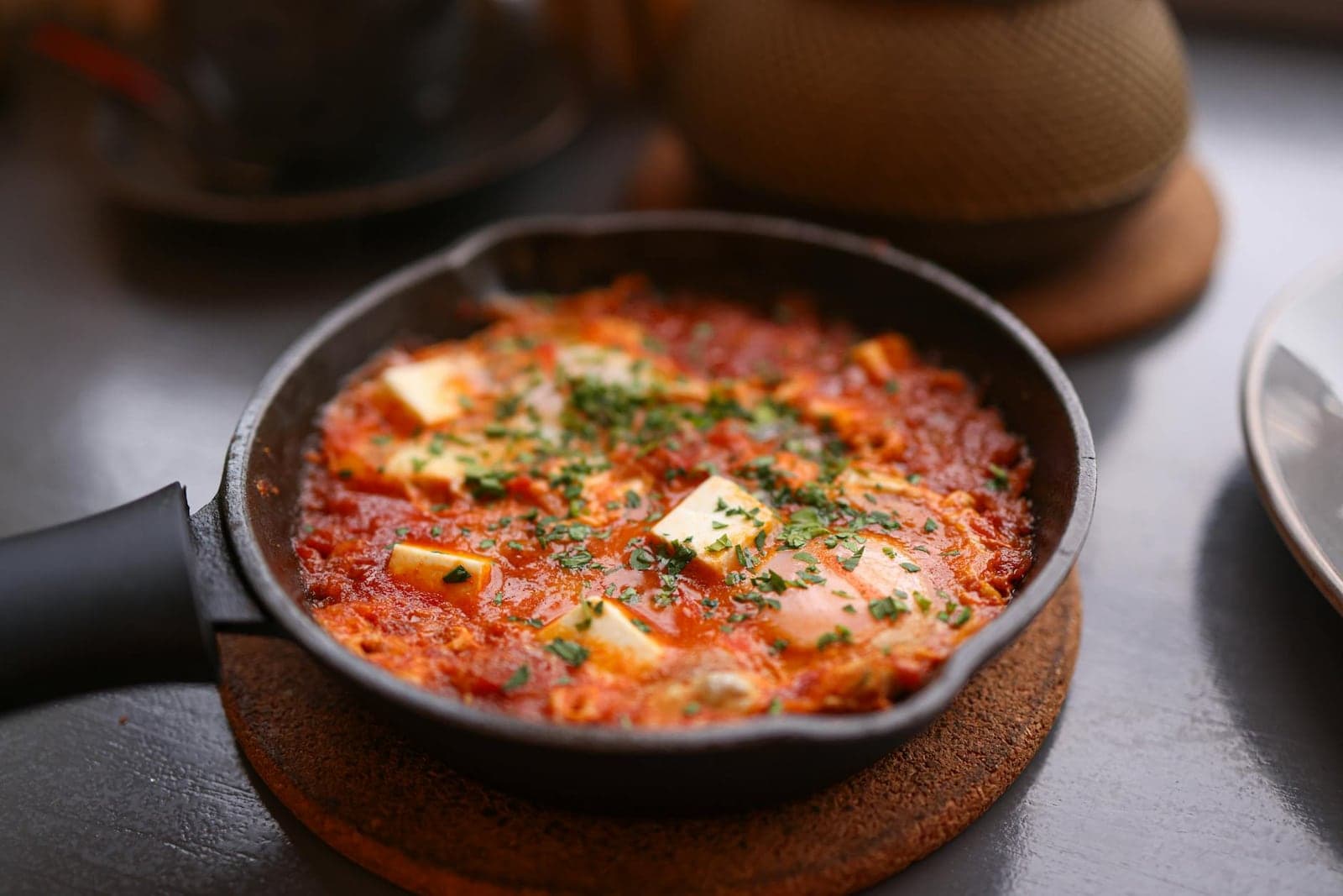 Shakshuka with feta in a skillet with poached eggs, tomato sauce, and fresh herbs