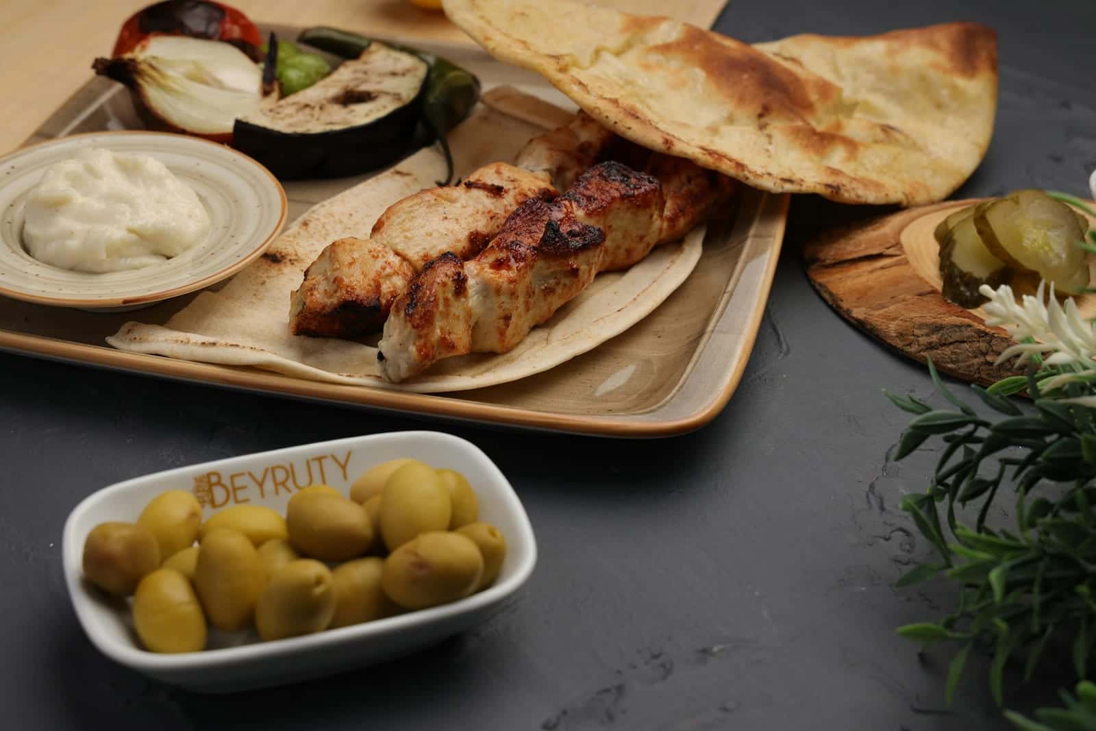 Shish tawook chicken skewers served with flatbread, olives, onions, and creamy sauce