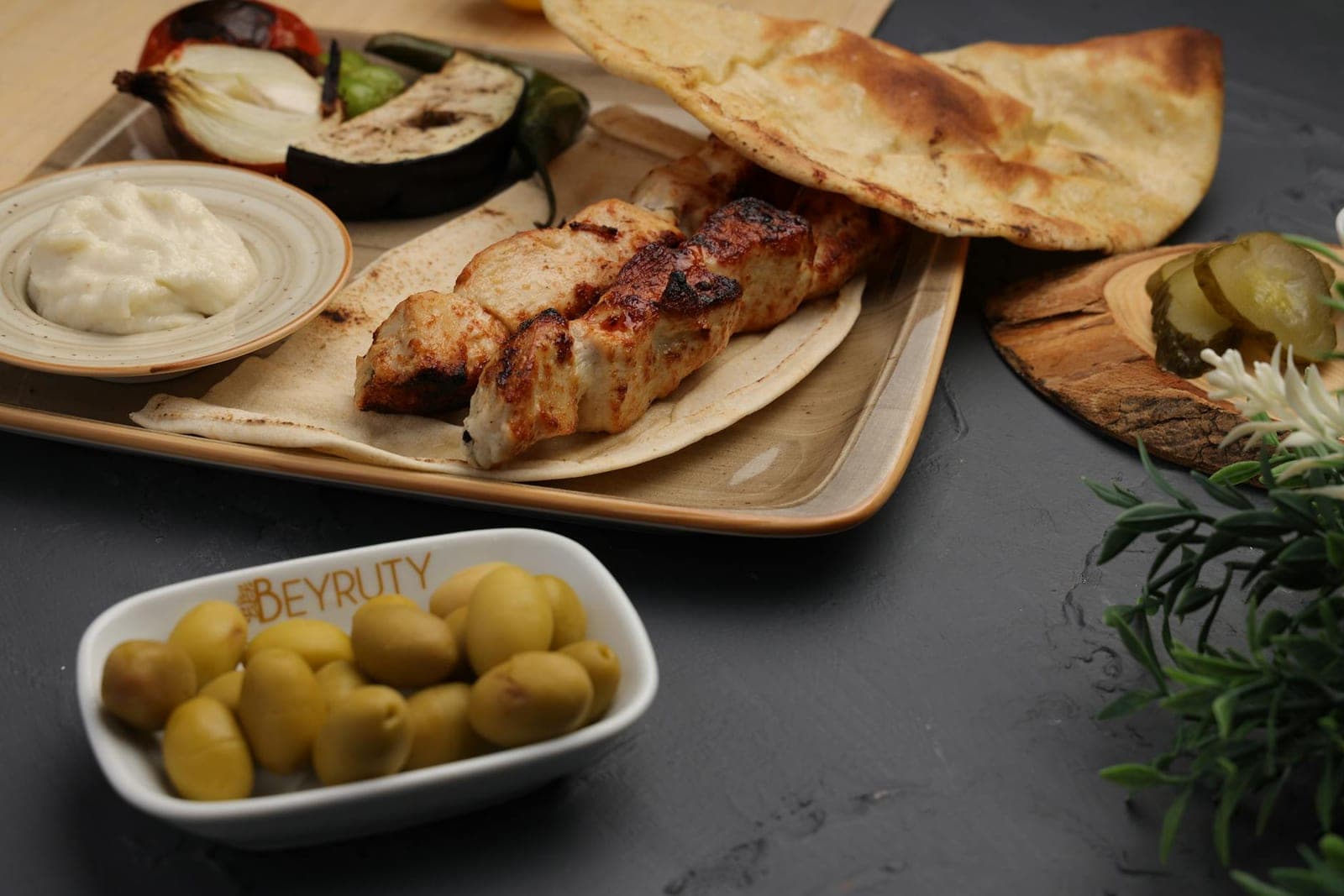 Shish tawook chicken skewers served with flatbread, olives, onions, and creamy sauce