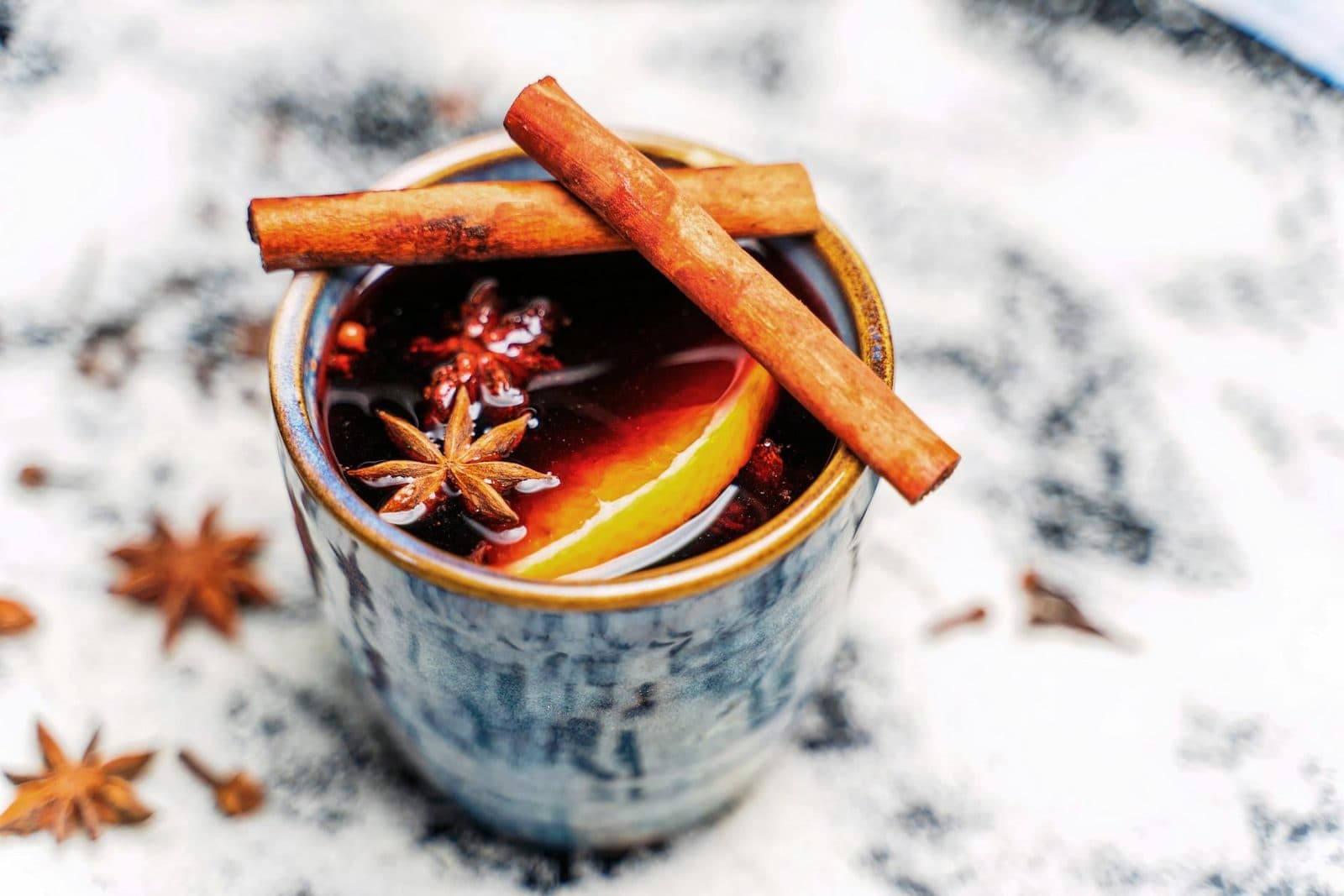 Spiced mulled wine in a cup with cinnamon sticks, star anise, and orange garnish