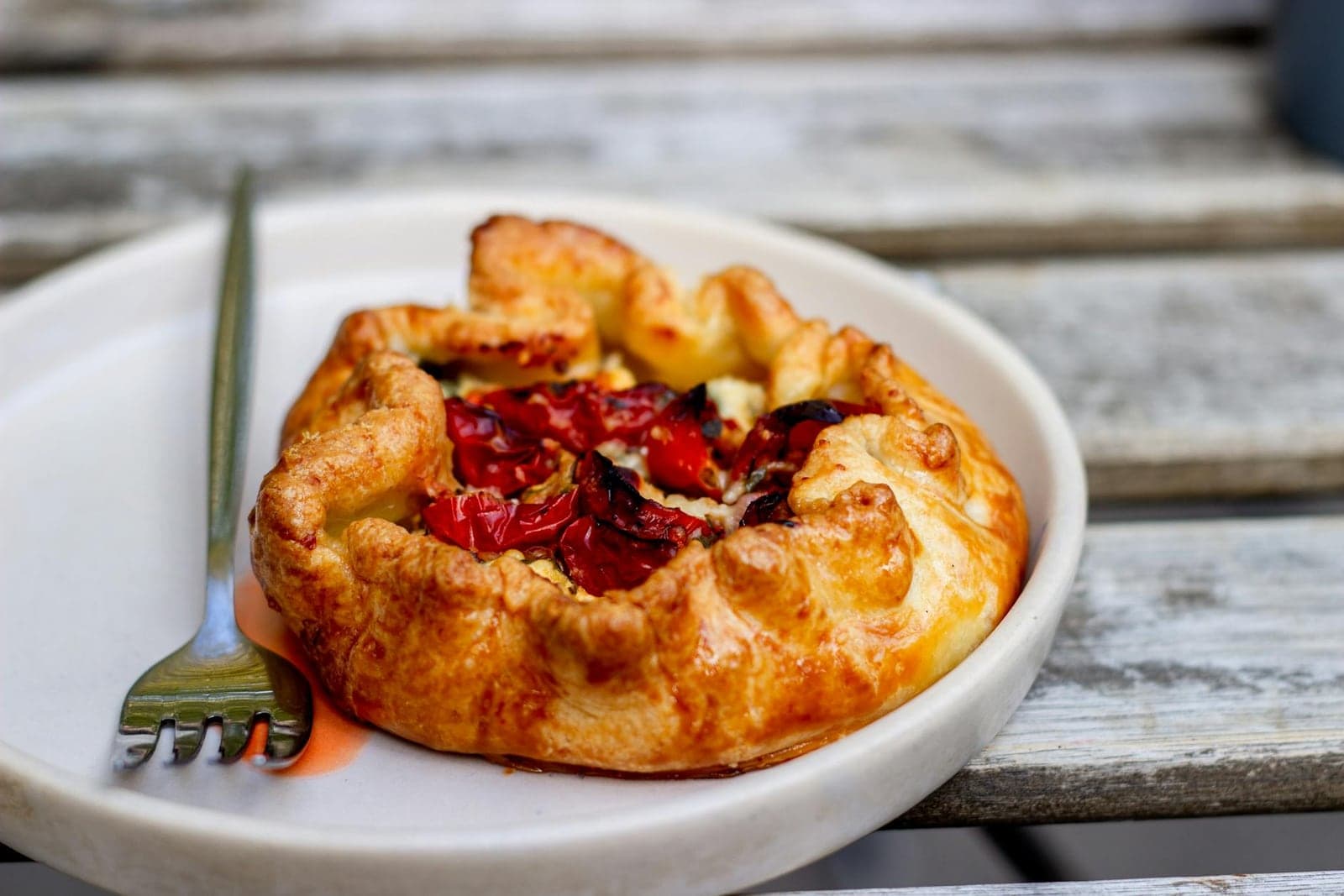 Summer tomato galette with a golden rustic crust and roasted tomatoes on a white plate