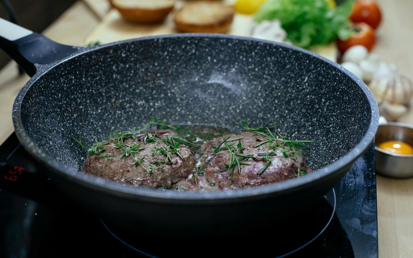 Tteok-galbi Korean beef patties browning in a skillet with herbs