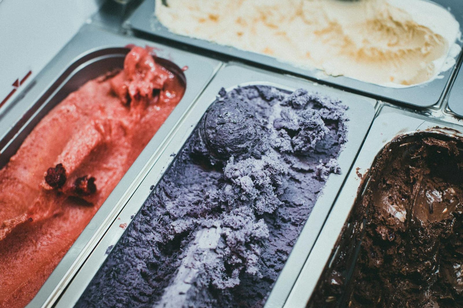 Ube ice cream in a metal tray with purple color and other ice cream flavors nearby