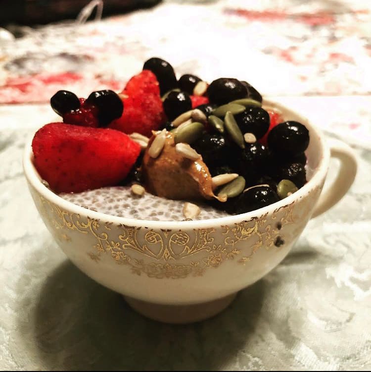 Glass jar of chia pudding topped with fresh mixed berries and a drizzle of honey