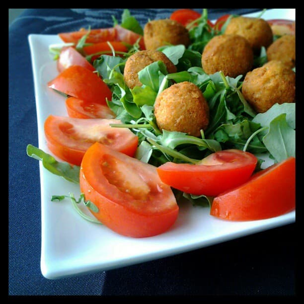 Crispy baked falafel arranged on a plate with tahini sauce and fresh herbs